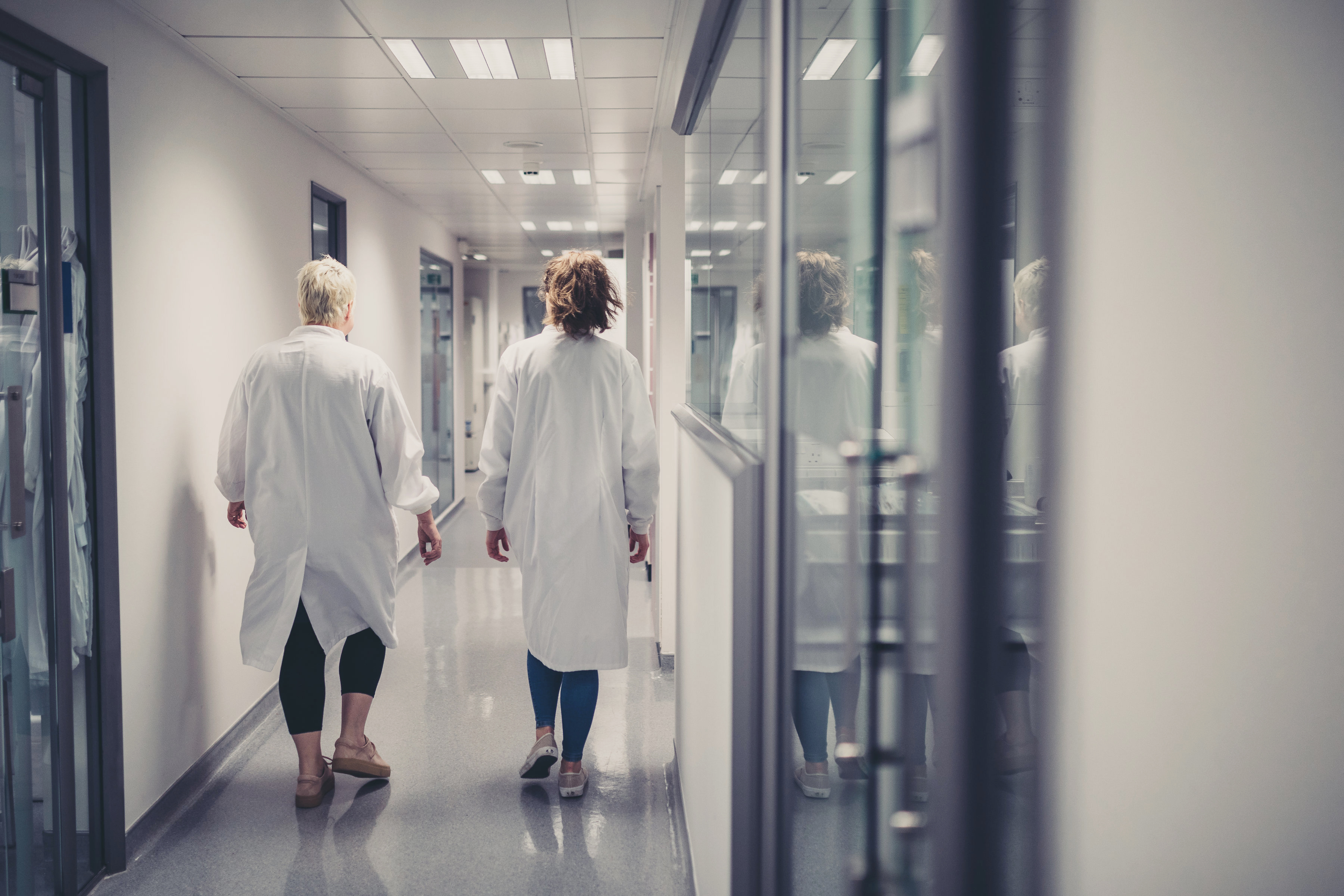 two scientists wearing white coat walking down corridor
